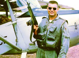 real life superhero posing next to his vehicle of choice, the O-1 Bird Dog