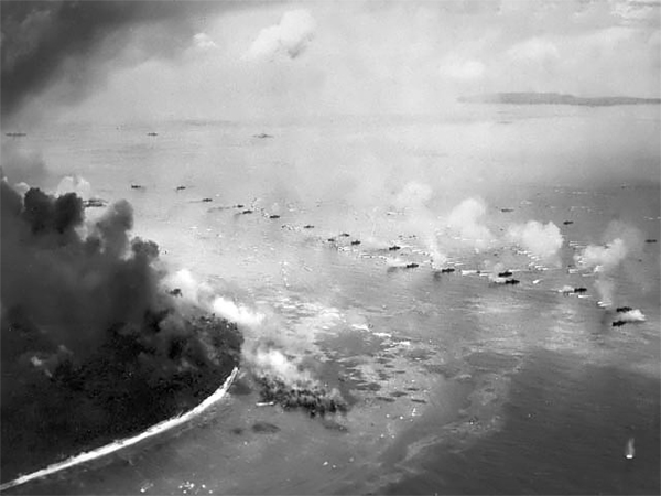 The first wave of LVTs moves toward the invasion beaches, passing through the inshore bombardment line of LCI gunboats on September 15, 1944. Cruisers and battleships are bombarding from the distance. The landing area is almost totally hidden in dust and smoke. 